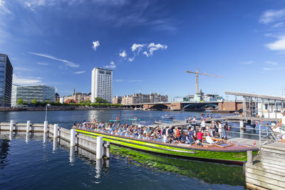Boats in river by buildings against sky