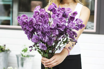 Midsection of woman holding purple flowers