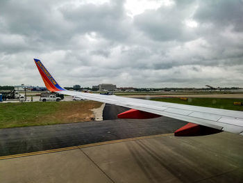 Airplane flying over airport runway against sky