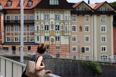 Side view of woman standing by building in city