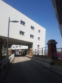 Road by buildings against clear blue sky