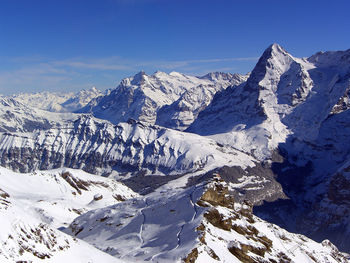 Scenic view of snow covered mountains against blue sky