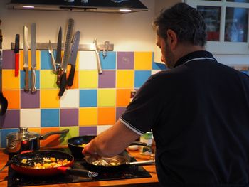 Rear view of man preparing food in kitchen