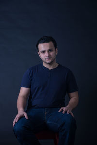 Portrait of confident young man against black background