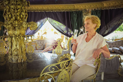 Elderly woman traveler sitting alone on the terrace of coffee shop