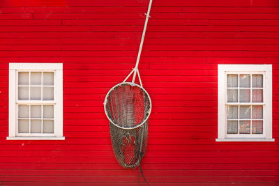 Fishing net hanging on red wall of house