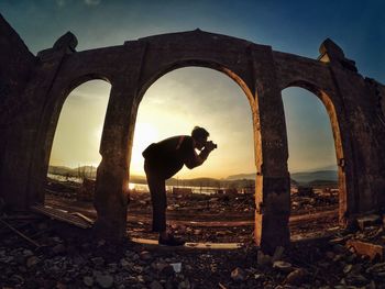 Man standing by abandoned built structure against sky