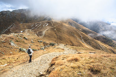 Rear view of woman hiking on trail at mountain