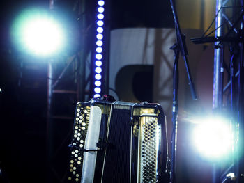 Close-up of accordion against illuminated stage lights at night