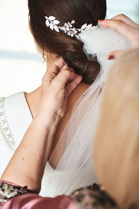 Bridesmaid tying hair of bride