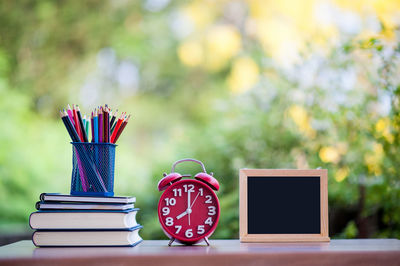 Colorful pencils with books and alarm clock on table