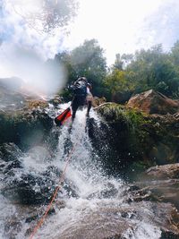 Man surfing on rocks against mountains