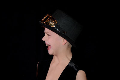 Portrait of young woman wearing hat against black background