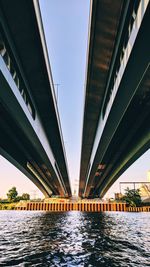 Low angle view of bridge over river against sky in city