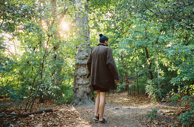 Full length rear view of woman standing on tree trunk