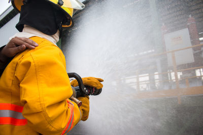 Side view of firefighter spraying water on house