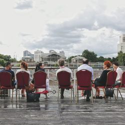 People sitting on table in city against sky