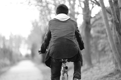 Rear view of teenage boy cycling on road