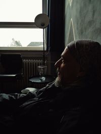 Side view portrait of a young man drinking glass at home