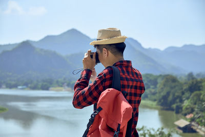 Man wearing hat standing against mountain range against sky