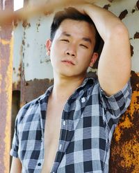 Portrait of man standing against rusty metal