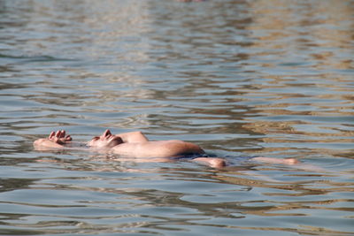 Shirtless man floating on water in lake