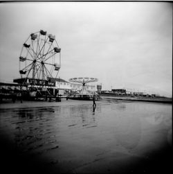 Ferris wheel by sea against sky