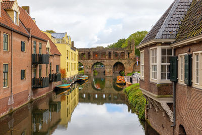 Arch bridge over canal amidst buildings against sky