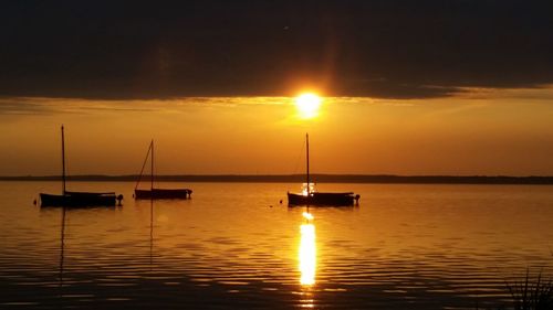 Silhouette boats sailing in sea against sky during sunset