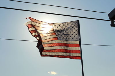 Low angle view of american flag waving against sky