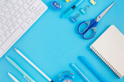 Directly above shot of office supplies over blue background