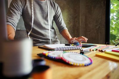 Midsection of man sitting on table at home