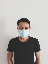 Portrait of young man standing against white background