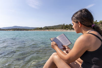 Teen girl reading a book and relaxing at the beach