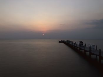 Pier over sea against sky during sunset