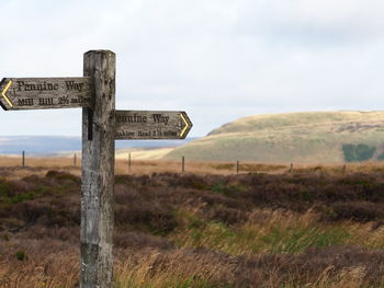 Wooden post on field against sky