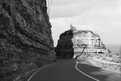 Road by rock formation against sky