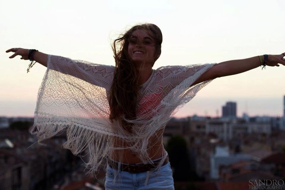 young adult, lifestyles, young women, person, portrait, standing, looking at camera, focus on foreground, casual clothing, leisure activity, three quarter length, front view, long hair, waist up, smiling, clear sky, confidence