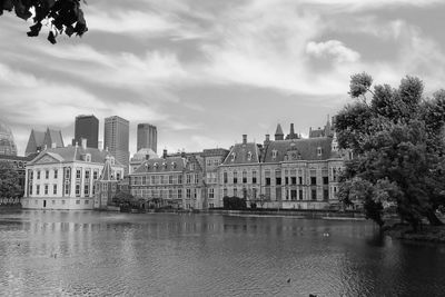 Buildings by river against sky in city