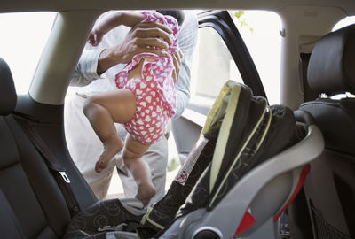 Midsection of father holding baby over car seat