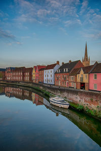 Buildings by river against sky in city