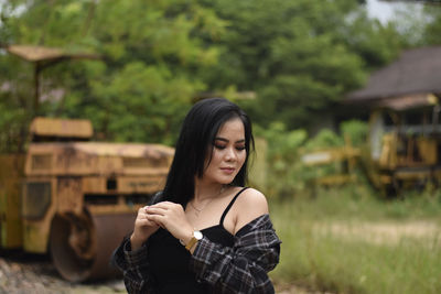 Portrait of young woman standing against trees