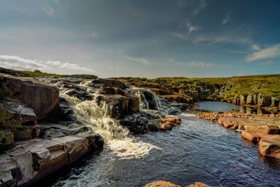 Scenic view of waterfall against sky