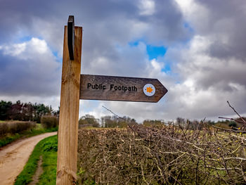 Information sign on field by road against sky