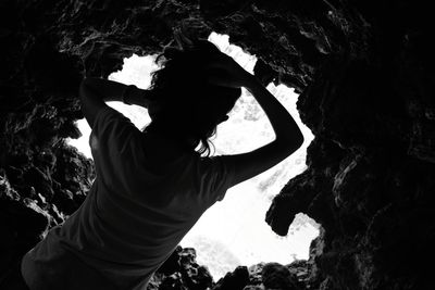 Rear view of woman standing in cave