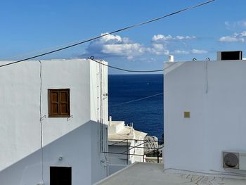 Buildings by sea against blue sky