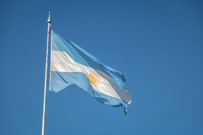 Low angle view of flag against clear blue sky