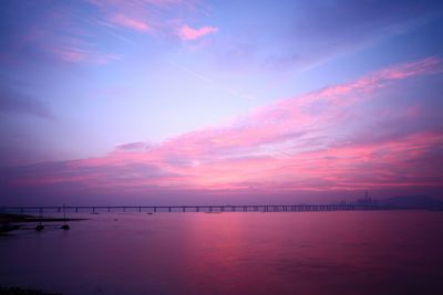 View of bridge over calm sea at sunset