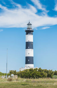 Lighthouse by sea against sky