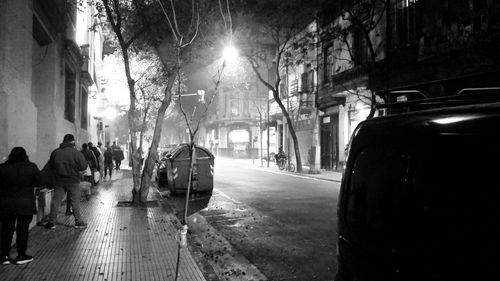 People walking on sidewalk in city at night